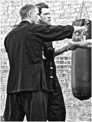 Wing Chun students drilling on the heavy bag against the brick dojo wall