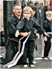 Head instructor Trevor Haines with young Five Animal Kenpo students in black gis at Dojo Chattanooga